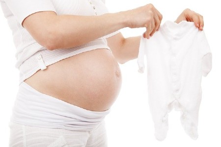 Sell back baby clothes-Pregnant women holding a white baby suit.