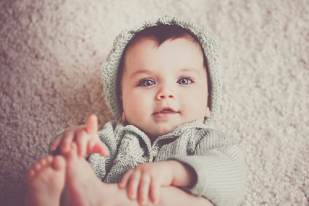  Sell back baby clothes-Baby laying on back wearing cute knitted outfit.