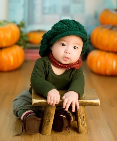 Sell back baby clothes-Baby sitting on the floor wearing super cute green outfit.