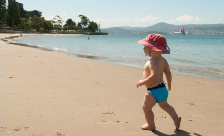 Best compostable nappies Australia-Baby on beach wearing a blue Eenee swim nappy