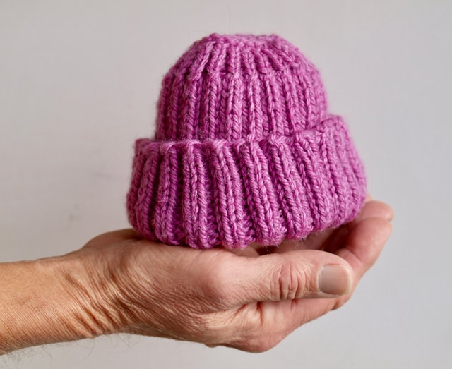 What's a baby registry?-A person holding a little purple baby hat.