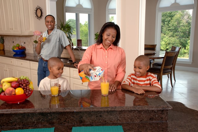 What's the Honest company?- Family of 4 are drinking juice in the kitchen.