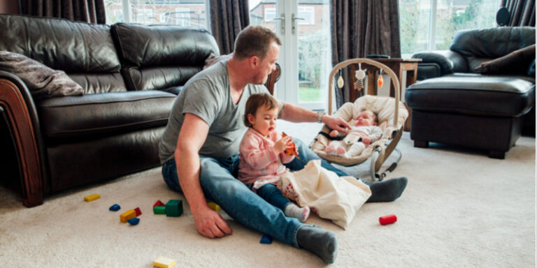 What is a baby rocker?-Dad at home on the floor with his two kids.