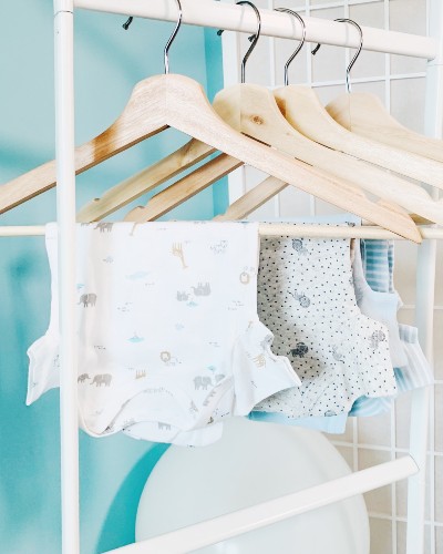 What're the best organic cotton baby clothes?-Baby bodysuits on coat hangers.