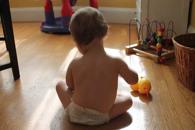 Are Under the Nile toys sold in Australia?-Baby playing with toys on a wooden floor.