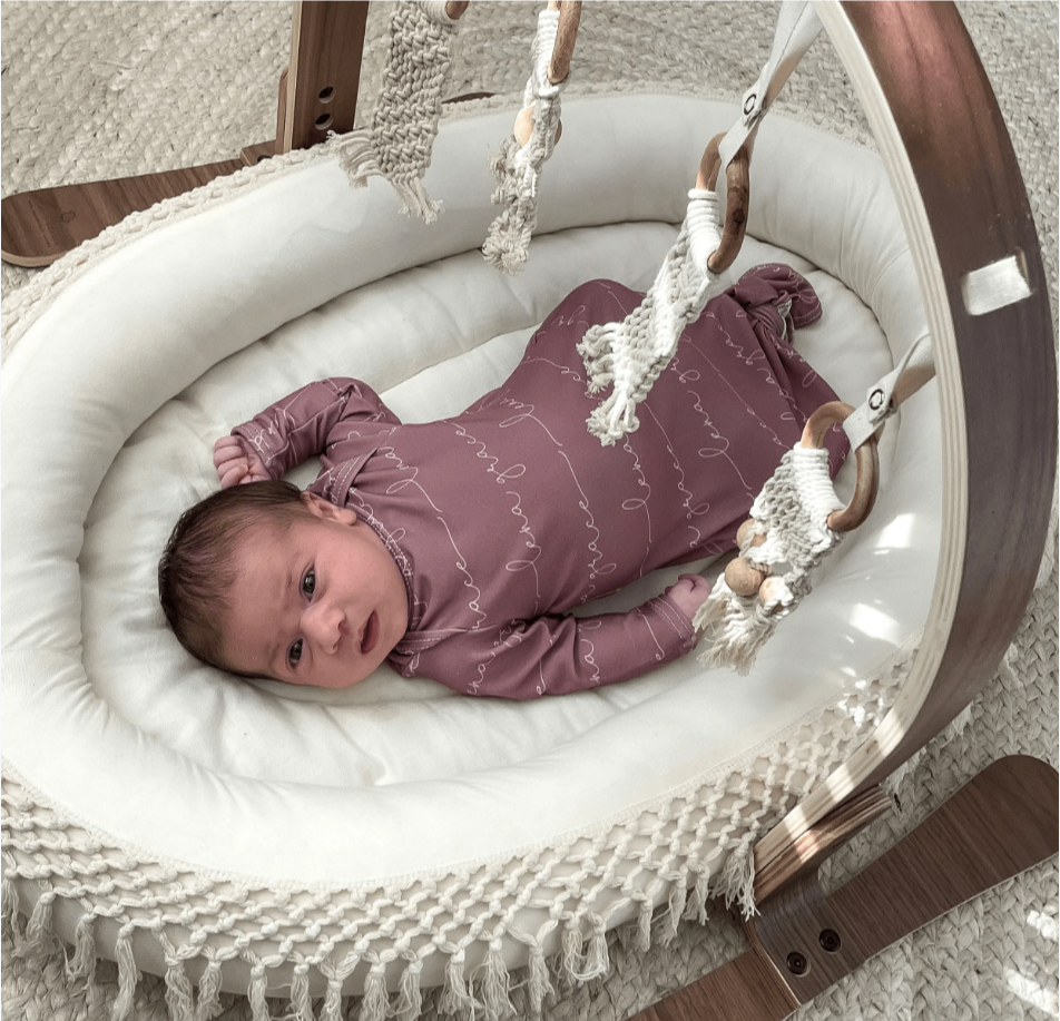 Organic baby clothes brands on Amazon.-Baby wearing a Finn and Emma organic footie while laying underneath Finn and Emma Baby Play gym.