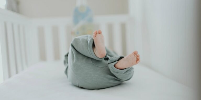 Mountain crib review.-Baby laying down in a white crib.