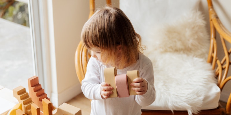 Organic Baby Clothes made with G.O.T.S Certified Organic Cotton.-Adorable kid playing with wooden construction blocks.